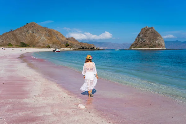Komodo Ulusal Parkı, Flores Adası, Endonezya, Asya 'da pembe plajda yürüyen bir kadın yolcu.