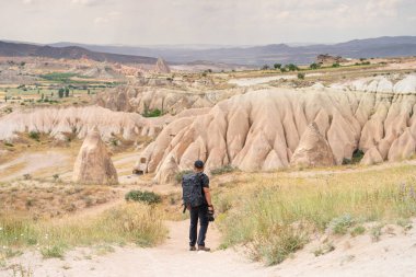 Sırt çantalı bir adam dağ yolunda yürüyor. Capadocia platosunda Goreme kasabasını arıyor.