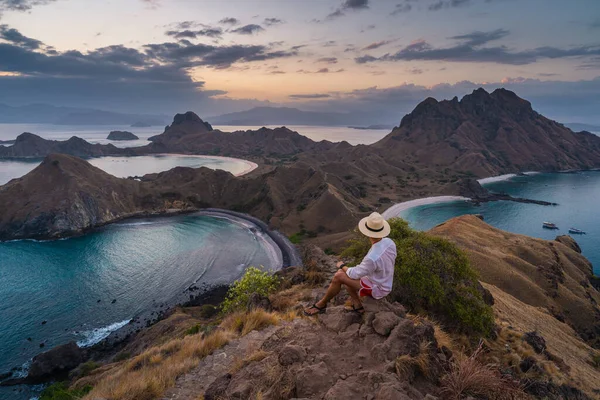 Padar adasının tepesinde oturan bir gezgin gün batımındaki güzel manzara hakkında konuşuyor, Komodo Ulusal Parkı, Endonezya, Asya 'daki Flores Adası.