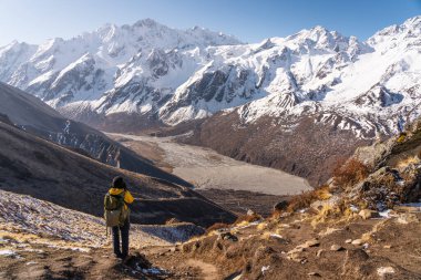 Kyanjin Ri bakış açısının tepesinde duran bir yürüyüşçü ve Asya, Nepal 'deki Himalaya sıradağlarının Langtang sıradağlarının fotoğrafını çekiyor.