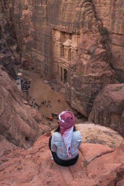 Petra harabesi ve antik şehir perspektifinde kayaların üzerinde oturan genç bir kadın gezgin Hazine, Hazine, Ürdün, Arap, Asya 'ya bakıyor.