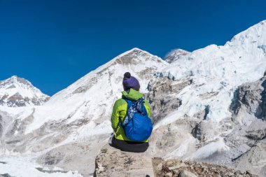 Himalayalar 'ın Nepal, Asya' daki dağları çevreleyen Everest ana kampında kayalıklarda oturan bir yürüyüşçü.