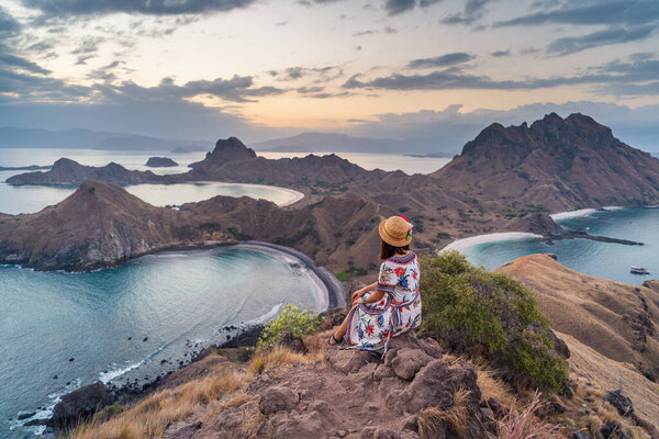 Young traveller sitting and relaxing on top of Padar island at sunset, Komodo national park in Indonesia, Asia