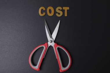 Makas iş gider kelime maliyet maliyet tasarrufu için keser. İş kavramı ve düşük ışık.