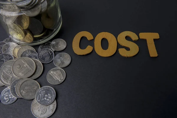 Monedas en el vaso con palabras cuestan. Concepto de ahorro de dinero y negocios . — Foto de Stock