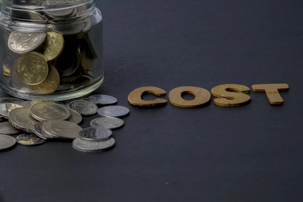 Monedas en el vaso con palabras cuestan. Concepto de ahorro de dinero y negocios . — Foto de Stock