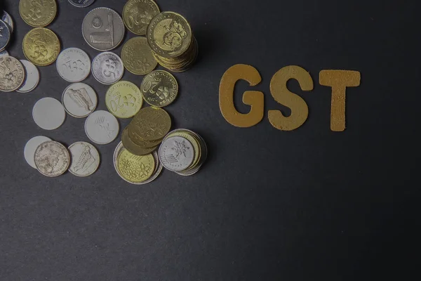 Монеты на доске со словом GST (налог на государственные услуги). Концепция бизнеса — стоковое фото