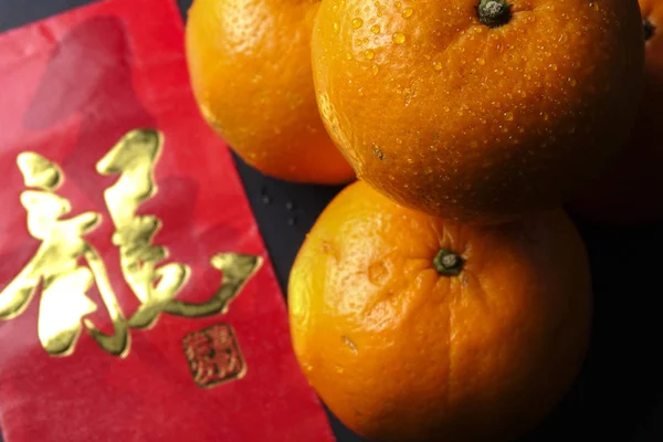 Decoraciones del festival de año nuevo chino, paquetes rojos y naranjas mandarín, carta china de oro significa suerte —  Fotos de Stock