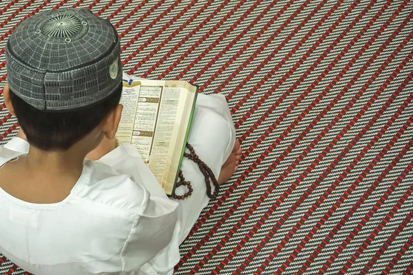 Boy reading al Quran during jesting month (Ramadhan) (em inglês). DOF e espaço de cópia . — Fotografia de Stock