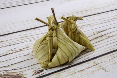Ketupat (pirinç hamur tatlısı) ahşap arka plan üzerinde. Genç Hindistan cevizi yapılan bir doğal pirinç kaplama pirinç eid Mubarak sırasında yemek pişirmek için yaprakları Ketupat olduğunu