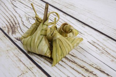 Ketupat (pirinç hamur tatlısı) ahşap arka plan üzerinde. Genç Hindistan cevizi yapılan bir doğal pirinç kaplama pirinç eid Mubarak sırasında yemek pişirmek için yaprakları Ketupat olduğunu