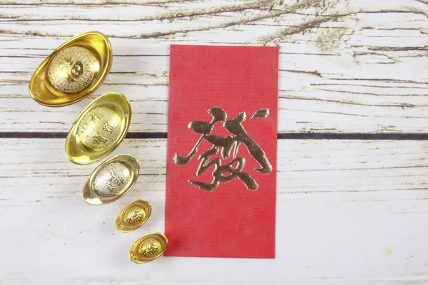 ゴールドインゴットと赤いお金パケット中国の新年の木製の背景にお祝いします 中国語の文字を意味する幸運 富と繁栄の画像で見ると — ストック写真