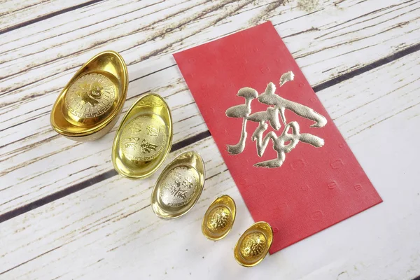 ゴールドインゴットと赤いお金パケット中国の新年の木製の背景にお祝いします 中国語の文字を意味する幸運 富と繁栄の画像で見ると — ストック写真