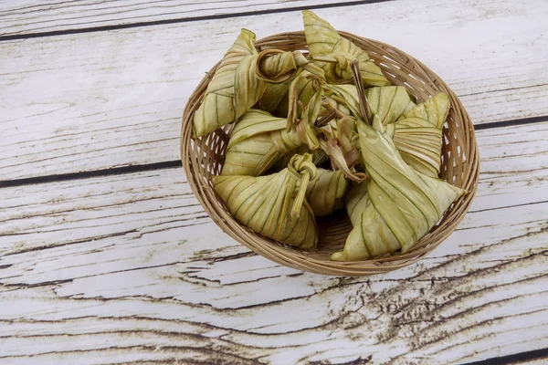 Ketupat (pirinç hamur tatlısı) ahşap arka plan üzerinde. Genç Hindistan cevizi yapılan bir doğal pirinç kaplama pirinç eid Mubarak sırasında yemek pişirmek için yaprakları Ketupat olduğunu