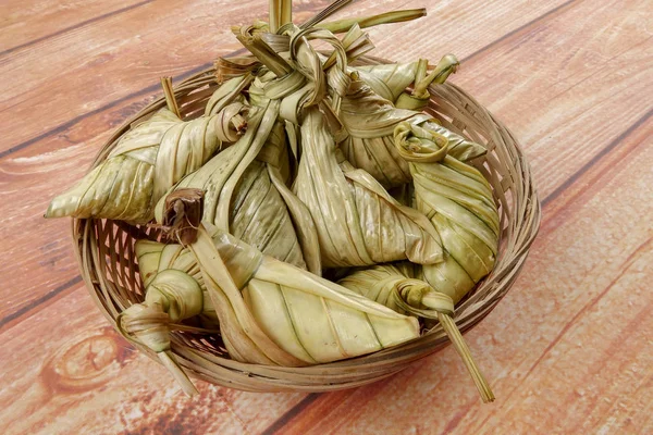 Ketupat (pirinç hamur tatlısı) ahşap arka plan üzerinde. Genç Hindistan cevizi yapılan bir doğal pirinç kaplama pirinç eid Mubarak sırasında yemek pişirmek için yaprakları Ketupat olduğunu