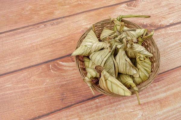 Ketupat (pirinç hamur tatlısı) ahşap arka plan üzerinde. Genç Hindistan cevizi yapılan bir doğal pirinç kaplama pirinç eid Mubarak sırasında yemek pişirmek için yaprakları Ketupat olduğunu