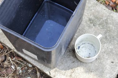 Stagnan çöp konteyner ve potansiyel musquitoes zemin ıslahı için plastik bardak suda. Bulanık resim.