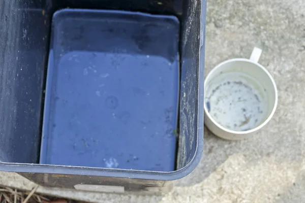 stock image Stagnan water in rubbish container and plastic cup potentially for musquitoes breeding ground. Blurred image.