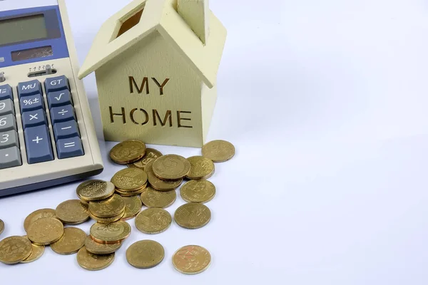 Деревянная модель дома с кучей монет и калькулятором . — стоковое фото