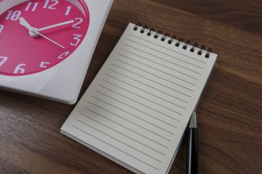 zaman yönetimi kavramsal, kitap, kalem ve ahşap saat