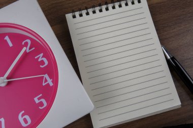 zaman yönetimi kavramsal, kitap, kalem ve ahşap saat