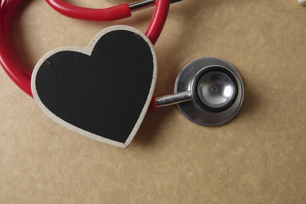 木製の背景に赤い聴診器。医療・健康の概念. — ストック写真