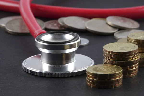 Red stethoscope,coin and puzzle on black. Medical concept. — Stock Photo, Image