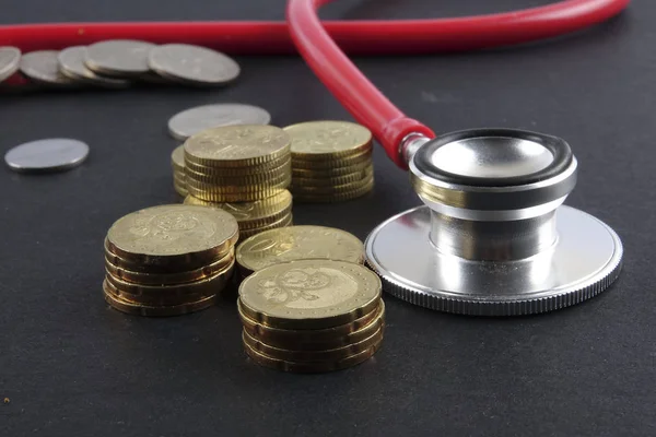 Červená stetoskop, mince a puzzle na černém pozadí. Lékařská koncepce. — Stock fotografie