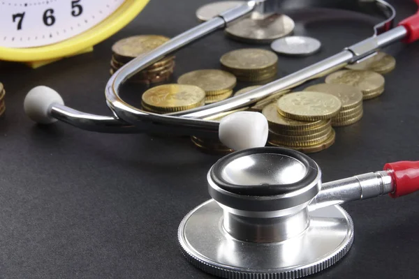 Red stethoscope and coins on black background. Medical — Stock Photo, Image