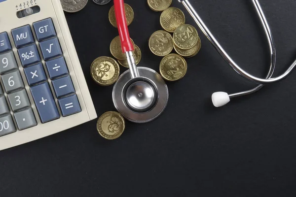 Czerwony stetoskop i monety na czarnym tle. Medyczne — Zdjęcie stockowe