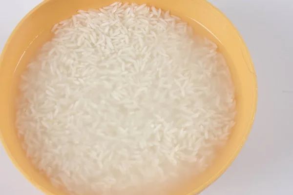 Remoje el arroz en un tazón amarillo sobre fondo blanco . — Foto de Stock