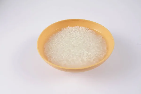 Soak rice in yellow bowl over white background. — Stock Photo, Image