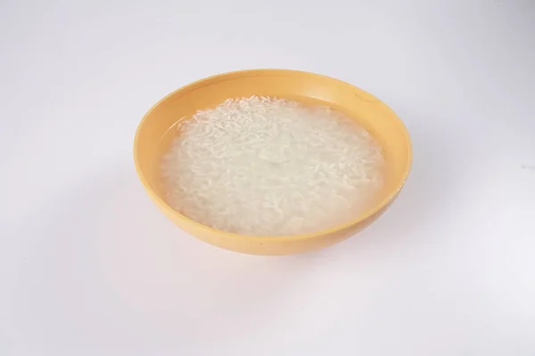 Immergere il riso in una ciotola gialla su sfondo bianco . — Foto Stock