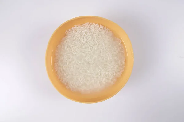 Immergere il riso in una ciotola gialla su sfondo bianco . — Foto Stock