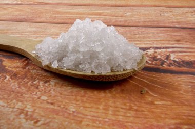 Bir tahta kaşık içinde deniz tuzu. Defne tuz olarak da adlandırılır veya güneş tuz, yemek ve kozmetik kullanılır. Kaba taneli mineral kristalleri.