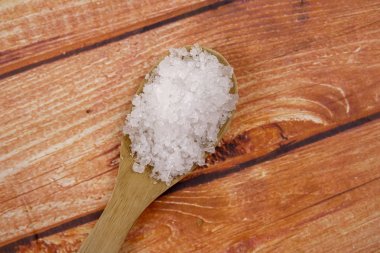 Bir tahta kaşık içinde deniz tuzu. Defne tuz olarak da adlandırılır veya güneş tuz, yemek ve kozmetik kullanılır. Kaba taneli mineral kristalleri.