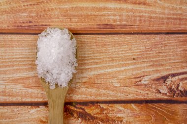 Bir tahta kaşık içinde deniz tuzu. Defne tuz olarak da adlandırılır veya güneş tuz, yemek ve kozmetik kullanılır. Kaba taneli mineral kristalleri.