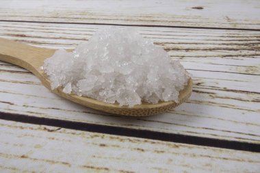 Bir tahta kaşık içinde deniz tuzu. Defne tuz olarak da adlandırılır veya güneş tuz, yemek ve kozmetik kullanılır. Kaba taneli mineral kristalleri.