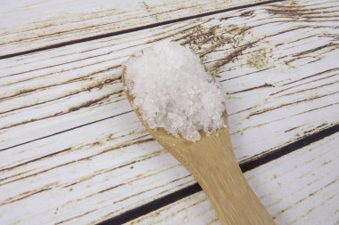 Bir tahta kaşık içinde deniz tuzu. Defne tuz olarak da adlandırılır veya güneş tuz, yemek ve kozmetik kullanılır. Kaba taneli mineral kristalleri.