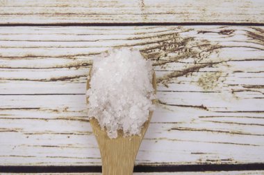 Bir tahta kaşık içinde deniz tuzu. Defne tuz olarak da adlandırılır veya güneş tuz, yemek ve kozmetik kullanılır. Kaba taneli mineral kristalleri.