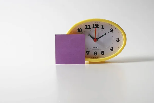 Yellow table clock with time management conceptual text on the note.