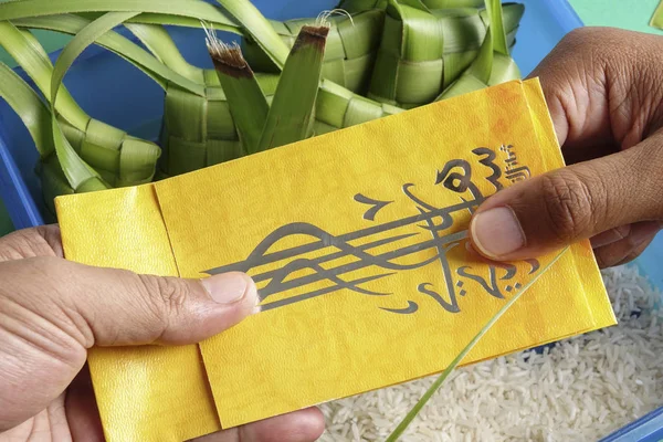 Giving and receiving money packet during Eid Fitri. Arabic character means Eid Mubarak