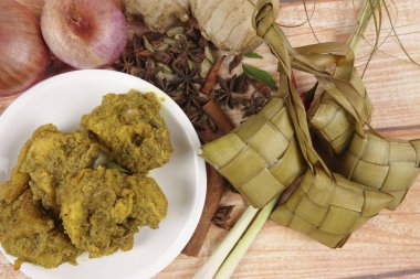 Malezya çanak Rendang Ayam veya kuru köri tavuk ve ahşap arka plan üzerinde Ketupat Nasi (pirinç hamur tatlısı)