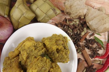 Malezya çanak Rendang Ayam veya kuru köri tavuk ve ahşap arka plan üzerinde Ketupat Nasi (pirinç hamur tatlısı)