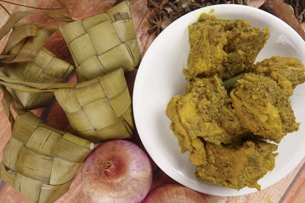 Malezya çanak Rendang Ayam veya kuru köri tavuk ve ahşap arka plan üzerinde Ketupat Nasi (pirinç hamur tatlısı) — Stok fotoğraf