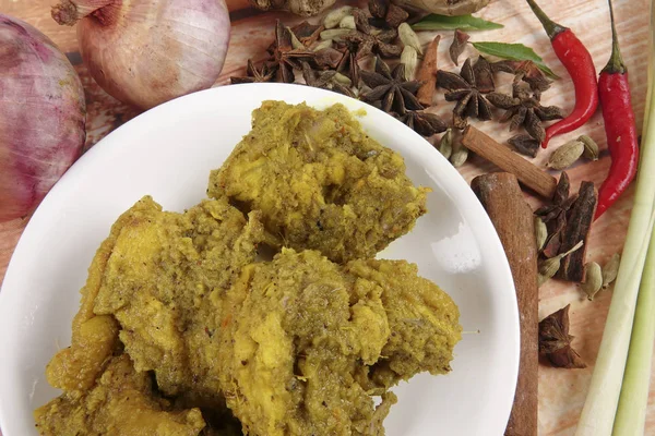 Malaysian dish Rendang Ayam or dry curry chicken and Ketupat Nasi (Rice Dumpling) over wooden background — Stock Photo, Image