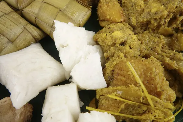 Малайзийское блюдо Ренданг Аям или сухой цыпленок карри и Кетупат Наси (Rice Dumpling) на деревянном фоне — стоковое фото