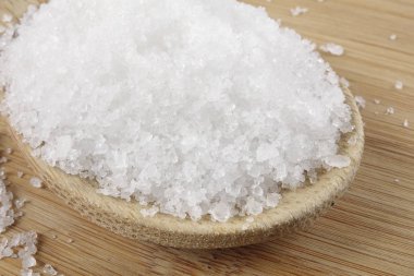 Tahta kaşık tuz ahşap arka plan üzerinde yakın çekim.