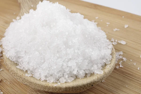 Close up of salt on wooden spoon over wooden background. — Stock Photo, Image