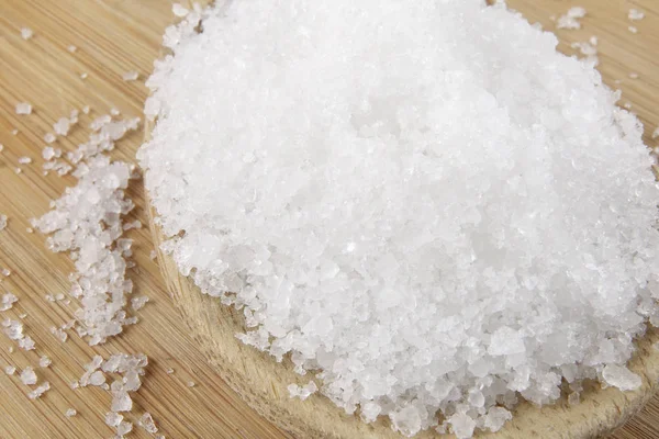 Close up of salt on wooden spoon over wooden background. — Stock Photo, Image